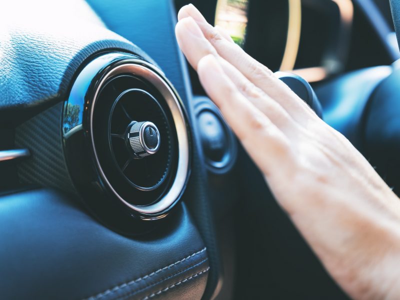 Closeup image of a hand checking the air conditioner system in the car