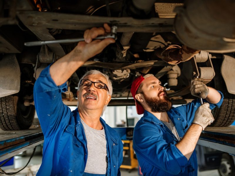 young-and-mature-technicians-of-car-repair-service-fixing-details-of-car-motor